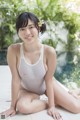 A woman in a white bathing suit sitting on the edge of a pool.