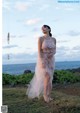 A woman in a white dress standing on a grassy hill.